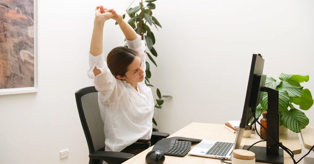 woman doing office stretches at ergonomic workstation